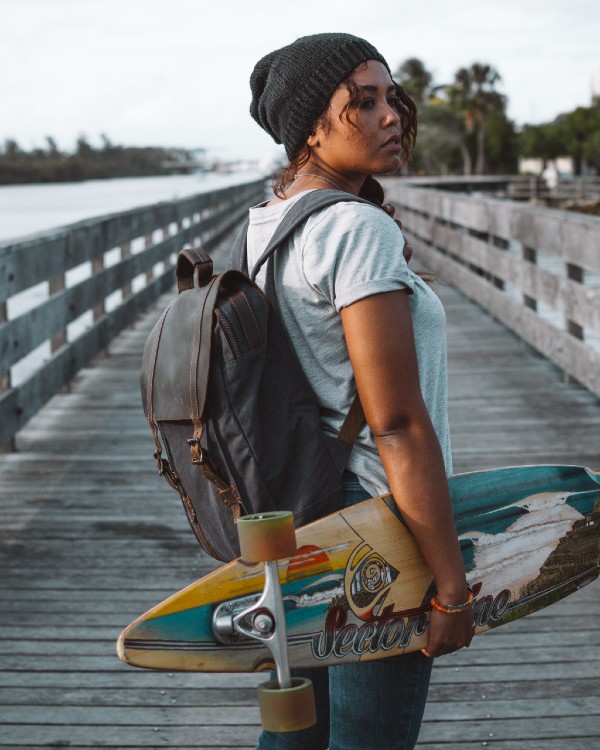A girl holding a longboard on the docks