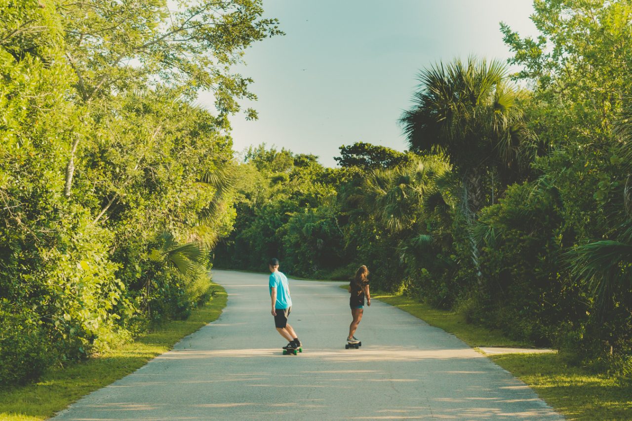 2 guys riding longboards on the road