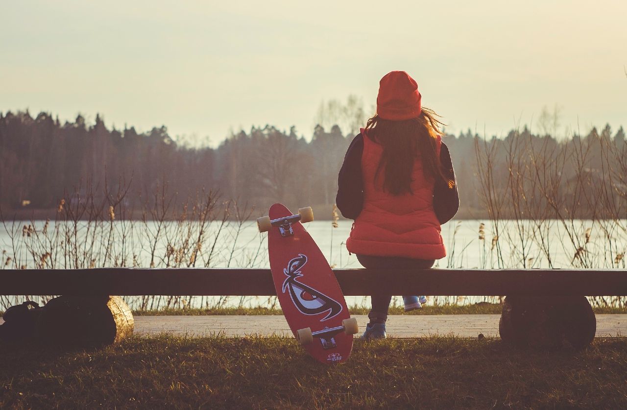 girl with a longboard sitting on bench