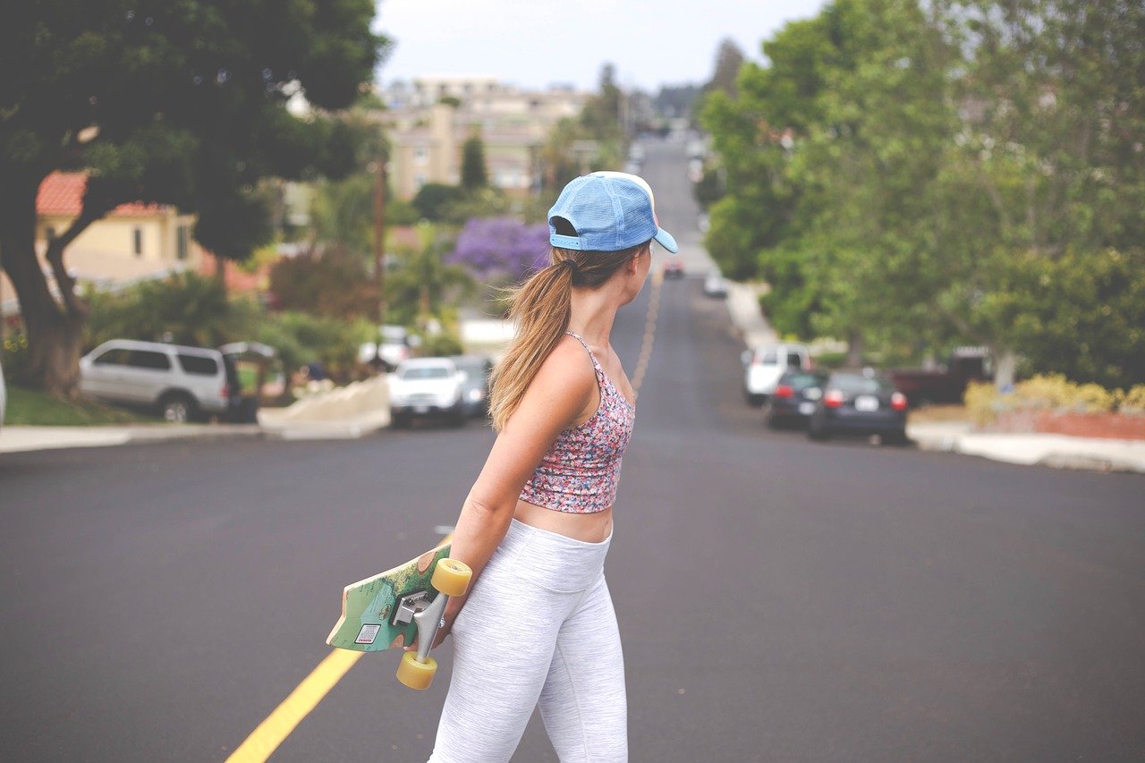 girl posing in the middle of the raod with a skateboard